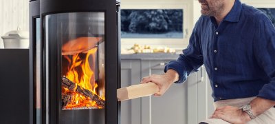 Jøtul F 373 Advance mit einem Mann, der Holzscheite hinzufügt