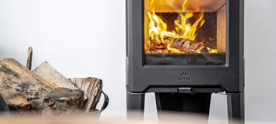 Jøtul F 163 schwarzer Holzofen mit Holzscheiten an der Seite und weißer Wand hinten 