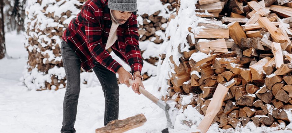 Mann hackt im Winter Holz 