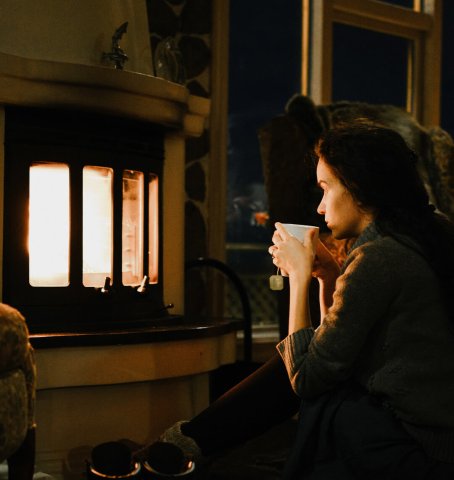 Dame, die abends vor dem Kamin sitzt